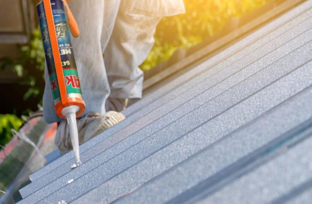 A man applies roofing material using a spray gun, demonstrating a technique for roof maintenance or installation.