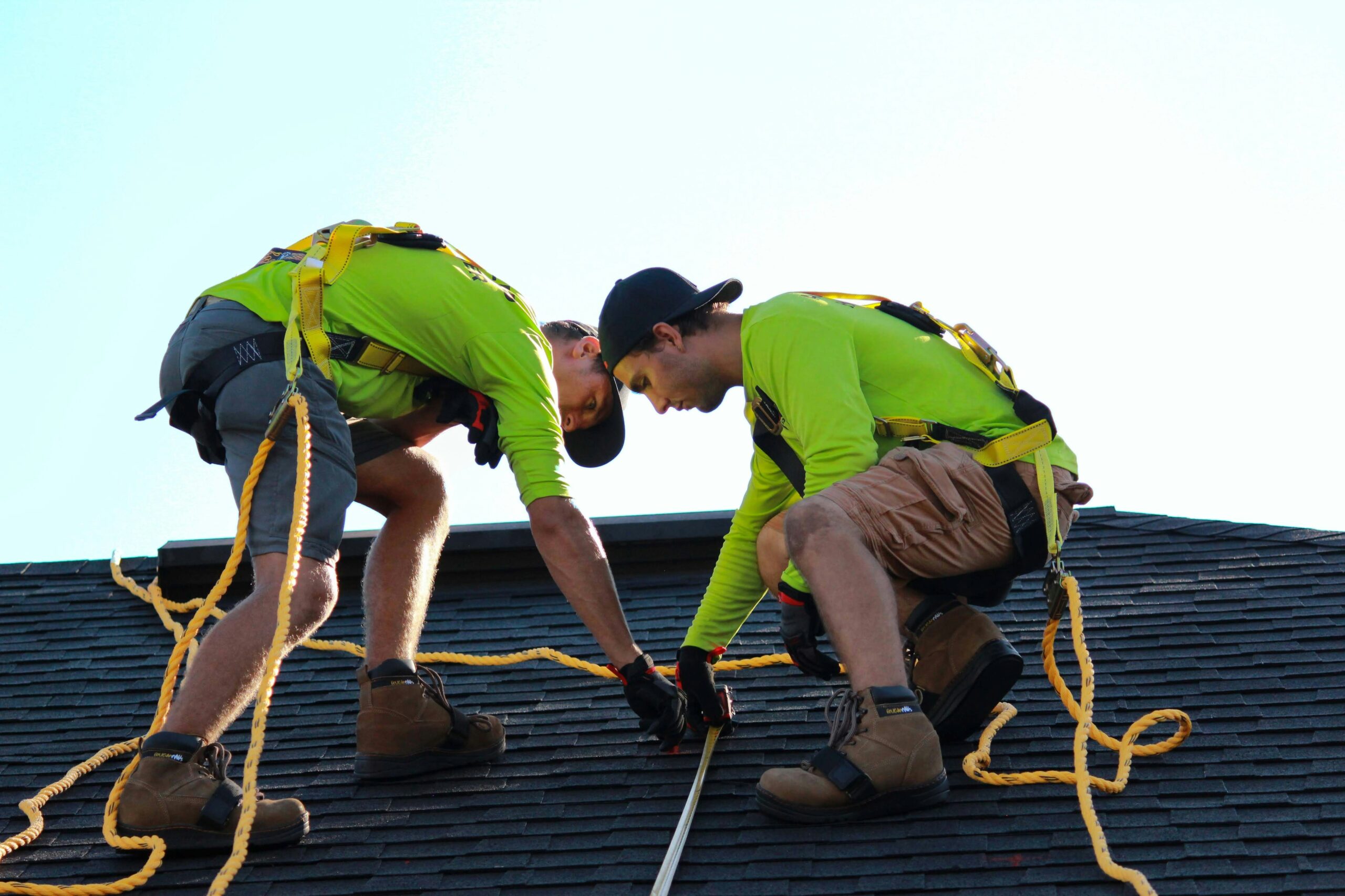 Two men in green shirts working on a roof, focused on restoration tasks in Sydney.